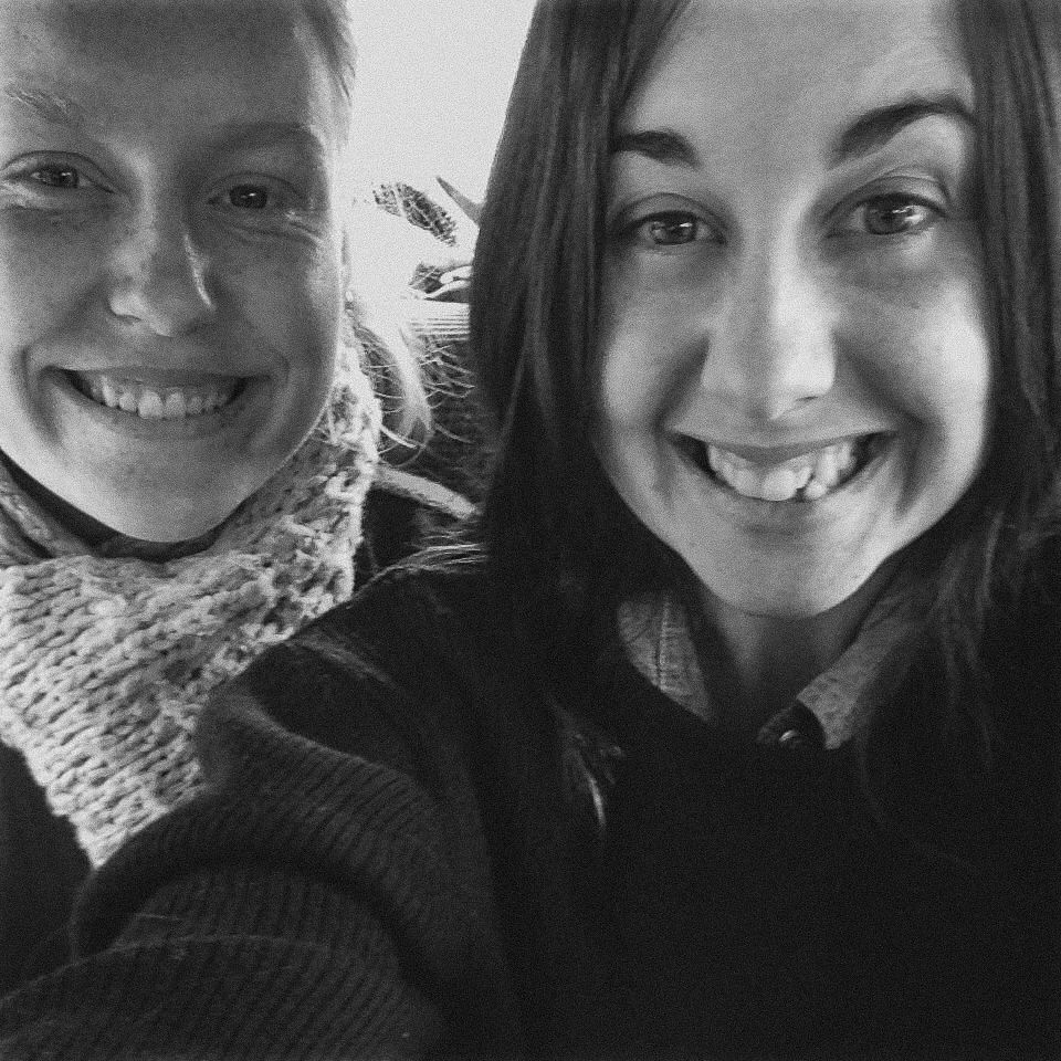 two ladies walking on sidewalk with black backpacks